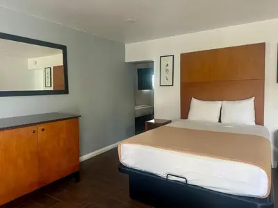 a hotel room with a bed and a mirror at Oceanside Inn & Suites in Oceanside