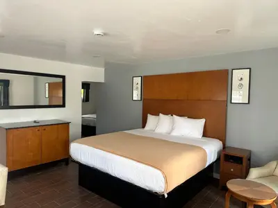 a hotel room with a bed and a chair at Oceanside Inn & Suites in Oceanside