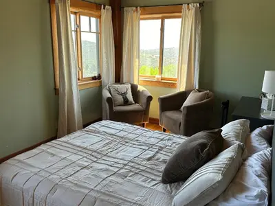 a bedroom with a bed and two chairs and a window at Sunset-Ridge in Alpine