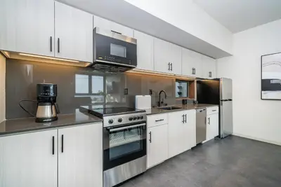 a kitchen with white cabinets and a stove top oven at City24 Condo Hotel Little Italy Mission Hills in San Diego