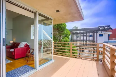 a room with a balcony with a red couch at Steps 2 Ocean & Surfing Ocean Views Rooftop Deck in San Diego