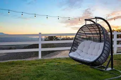 a wicker swing sitting on the grass near a fence at Grenache Estate - Nestled in Temecula Wine Country in Temecula