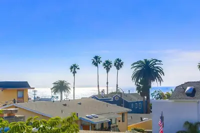 a view of a beach with palm trees and houses at Ocean-view home blocks to beach with private hot tub & rooftop deck in San Diego