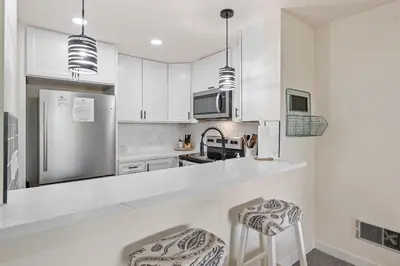 a kitchen with white cabinets and a stainless steel refrigerator at G6 - Answered Prayers Cottage in Oceanside
