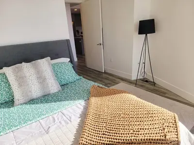 a bed with green and white pillows and a lamp at Bayviews Lux One-bedroom Apartment 1min to Petco Park Convention Center Gaslamp Pool, Hot Tub in San Diego