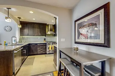 a kitchen with wooden cabinets and a large painting on the wall at Playa Del Sur Getaway La Jolla in San Diego