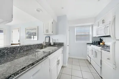 a white kitchen with white cabinets and granite counter tops at 1404 W Oceanfront B in Newport Beach