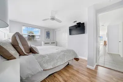 a white bedroom with a bed and a flat screen tv at 1404 W Oceanfront B in Newport Beach