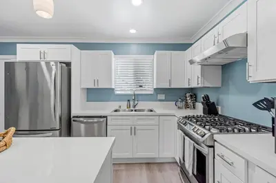 a kitchen with white cabinets and a stainless steel refrigerator at Carlsbad Blvd Villa in Carlsbad