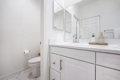 a white bathroom with a toilet and a sink at Brand New Stunning 4BR Townhome in Lemon Grove