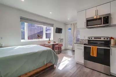 a bedroom with a bed and a kitchen with a stove at Studio Verde- Free Parking, Central in San Diego