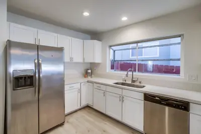 a kitchen with white cabinets and a stainless steel refrigerator at Urban Spanish Bungalow in San Diego