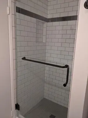 a shower with white tiled walls and a black and white at 124 Thirty Fourth Street B in Newport Beach