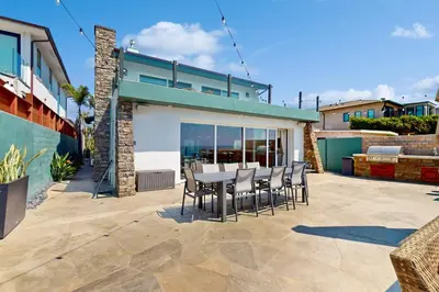 a patio with a table and chairs in front of a building at Neptune Sunset Shores Oceanfront in Encinitas