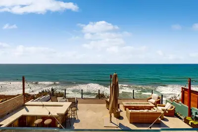 a patio with a table and umbrella and the ocean at Neptune Sunset Shores Oceanfront in Encinitas