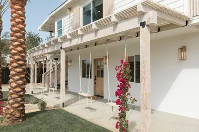 a white house with a porch with flowers on it at Elegant 2BR with Outdoor Space in Carlsbad