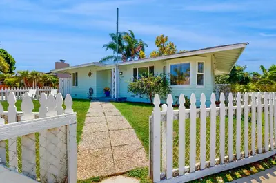 a white picket fence in front of a blue house at Blue Oasis Cozy Home in San Diego