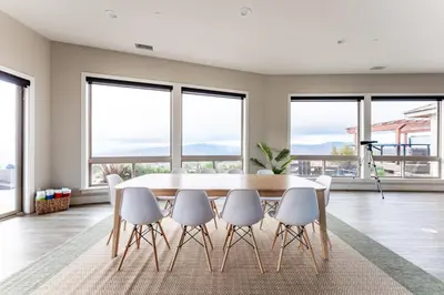 a dining room with a table and chairs and windows at Vista Grande home in Ramona