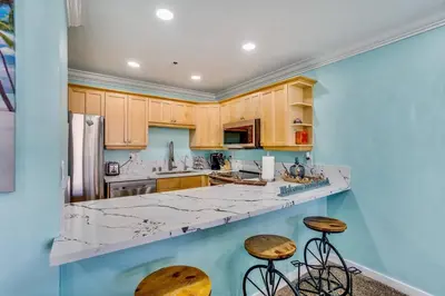 a kitchen with wooden cabinets and marble counter tops at Beach Front Paradise - Entire Condo- Crystal Pier in San Diego