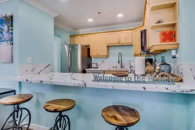 a kitchen with wooden stools and a counter top at Beach Front Paradise - Entire Condo- Crystal Pier in San Diego