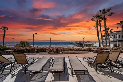 a sunset at the beach with chairs and a table at Beach Front Bliss - Entire Condo - Crystal Pier in San Diego