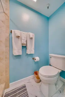 a bathroom with a toilet and towels on a blue wall at Beach Front Bliss - Entire Condo - Crystal Pier in San Diego