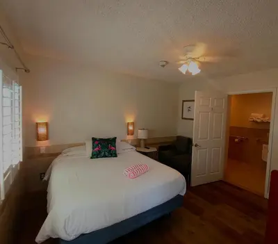 a bedroom with a white bed and a chair at El Rancho Motel in San Diego