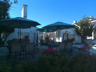 a group of chairs and umbrellas in front of a house at El Rancho Motel in San Diego