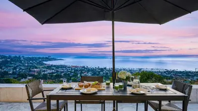 a table with an umbrella with a view of the city at Jewel by AvantStay Panoramic Ocean Views in La Jolla in San Diego
