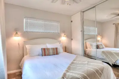 a bedroom with a white bed and a mirror at Beachside Bliss Spacious 3BR Retreat, Steps to Ocean in Oceanside