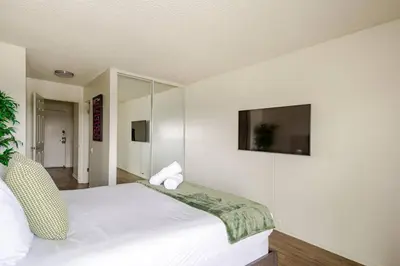 a bedroom with a white bed and a flat screen tv at Cozy Coastal Retreat Newport Beach in Newport Beach
