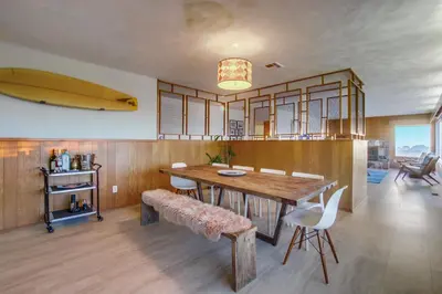 a dining room with a table and a surfboard on the wall at Red Hawk Coastal Estate in San Diego