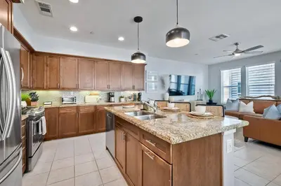 a kitchen with wooden cabinets and a large counter top at Blocks To Beach - Coastal Beach Decor - Garage Parking - Gated Community - 30 Day Fully Furnished in Oceanside