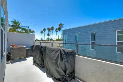 a balcony with a blue building with tarps on it at Blocks To Beach - Coastal Beach Decor - Garage Parking - Gated Community - 30 Day Fully Furnished in Oceanside