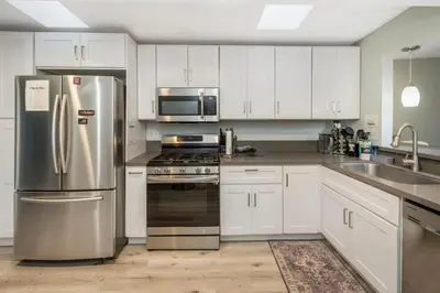 a kitchen with white cabinets and stainless steel appliances at Sunlit Shores beachside Bliss in San Diego
