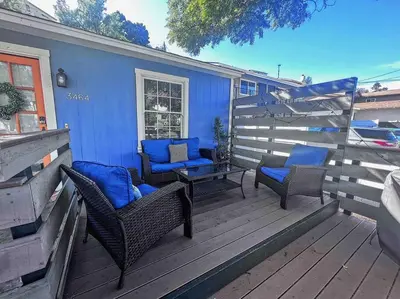 a deck with chairs and a table and a blue house at The Downtown Blue Bungalow Escape in San Diego