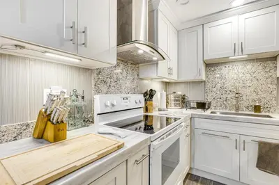 a white kitchen with white cabinets and white appliances at Oceanside Condo with Pool and Hot Tub Access! in Oceanside