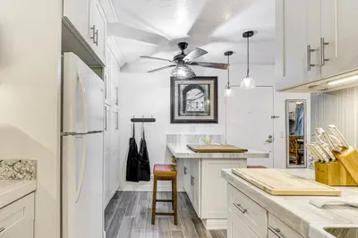 a kitchen with white cabinets and a ceiling fan at Oceanside Condo with Pool and Hot Tub Access! in Oceanside