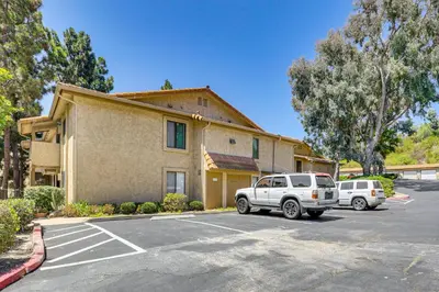 a building with two cars parked in a parking lot at Oceanside Condo with Pool and Hot Tub Access! in Oceanside