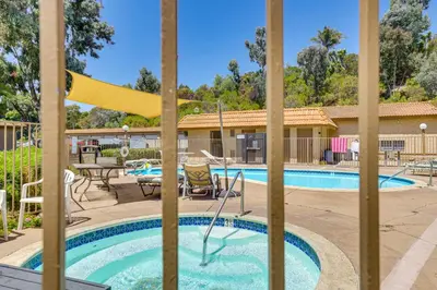 a pool at a resort with chairs and a table at Oceanside Condo with Pool and Hot Tub Access! in Oceanside