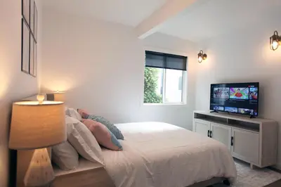 a white bedroom with a bed and a television at La Jolla Beach Villa Gem in San Diego
