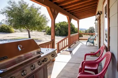 a porch with a stove and chairs on a house at Stylish Country Home with Hot Tub and Amazing Views on 40 Acres in Ranchita