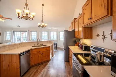a kitchen with wooden cabinets and a stainless steel refrigerator at Stylish Country Home with Hot Tub and Amazing Views on 40 Acres in Ranchita