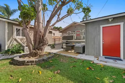 a house with a red door and a tree at Endless Summer Retreat - Beach - AC - Shops in San Diego