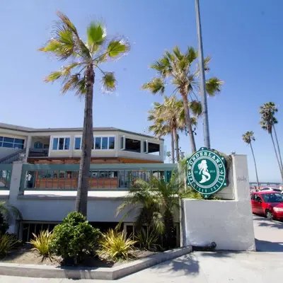 a sign in front of a building with palm trees at Endless Summer Retreat - Beach - AC - Shops in San Diego