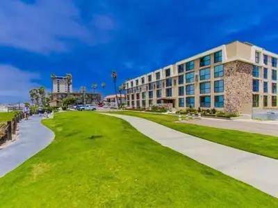 a building on the beach with a green lawn at Ocean Breeze 2 bedroom in San Diego