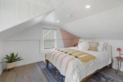 a white attic bedroom with a bed and a window at 5BD Home with outdoor space in Little Italy in San Diego