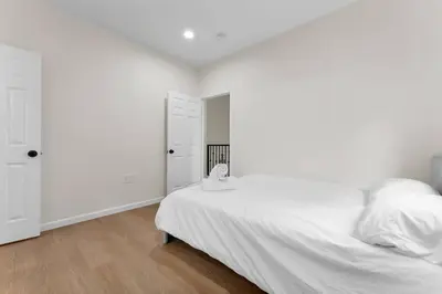 a white bedroom with a bed with white sheets and pillows at Urban Retreat Fun Relax Self Check-In Hot Tub Foosball Fire Pit Cornhole in The Woods Trailer Park