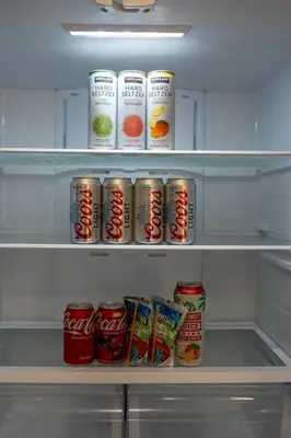 an open refrigerator filled with cans and canned food at Urban Retreat Fun Relax Self Check-In Hot Tub Foosball Fire Pit Cornhole in The Woods Trailer Park
