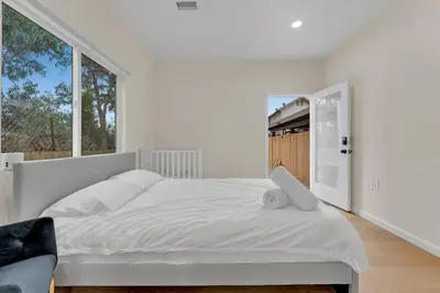a white bedroom with a large bed and windows at Urban Retreat Fun Relax Self Check-In Hot Tub Foosball Fire Pit Cornhole in The Woods Trailer Park